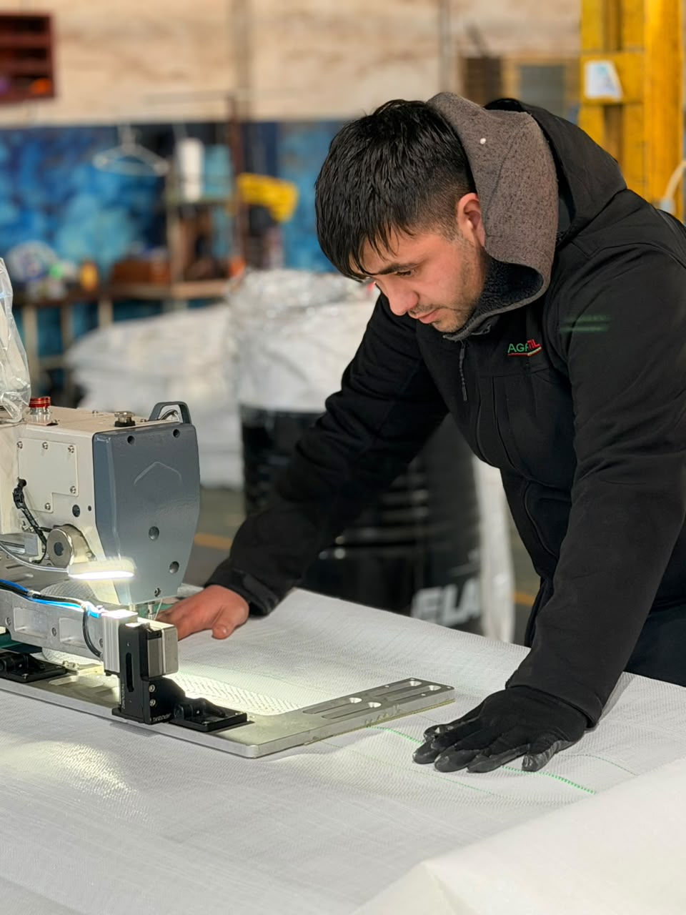 Operario confeccionando una lona en una máquina de coser industrial